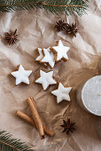 Cinnamon star biscuits, cinnamon sticks, star anise, candle and fir branches on brown paper