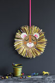 Lion's head made from cardboard and raffia decorating child's bedroom