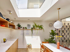 Light-flooded, open-plan kitchen with skylight and glass wall overlooking courtyard garden