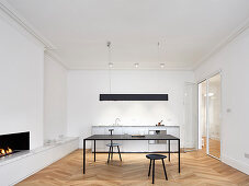 Kitchen counter, table and fireplace in open-plan interior with modern minimalist furnishings