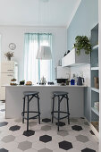Barstools at counter in open-plan kitchen with honeycomb floor tiles