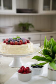 Cake topped with berries and posy of lily-of-the-valley on dining table