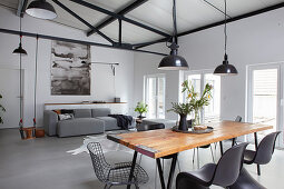 Rustic dining table, grey sofa and child's swing in loft apartment