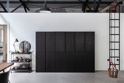 Black serving trolley next to black, industrial-style cupboard