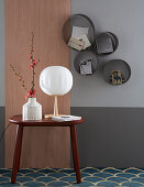 Wooden panel and side table next to round shelf modules on two-tone wall
