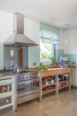 Stainless steel cooker with extractor hood next to wooden, open-fronted kitchen counter