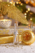 Wish list in tiny bottle surrounded by golden Christmas decorations