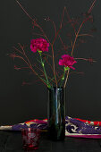 Modern arrangement of carnations and twigs in glass vase