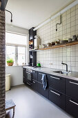 Fitted kitchen with dark cabinets and tiled wall