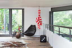 A black armchair, an animal fur rug, a cube seat and a red and white striped decorative object