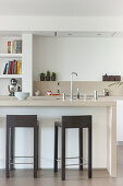 Angular barstools at island counter in beige modern kitchen