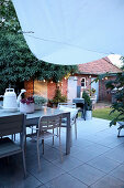 Tisch und Stühle auf der Terrasse im Hinterhofgarten bei Abendstimmung