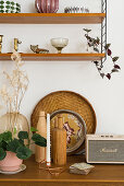 Vase, wooden bottle, tray and vintage radio below shelves or ornaments
