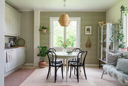 Round table and chairs in kitchen-dining room with patterned wallpaper