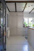 A view into a white kitchen with wooden floorboards