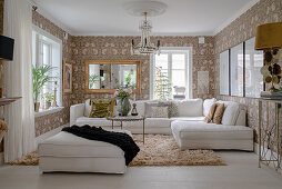 A white upholstered sofa in a living room with floral wallpaper