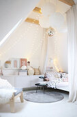 Fairy lights and paper lamps in teenager's attic bedroom decorated in white