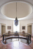 Circular galleried landing hung with a collection of colourful 19th and 20th century paintings
