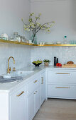 Marble, glazed tiles and golden accents in white kitchen