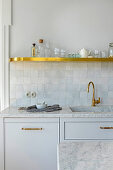 Marble, glazed tiles and golden accents in white kitchen