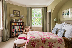 Tagesdecke mit Blumenmuster auf Bett und Vintage Bücherregal im viktorianischem Schlafzimmer