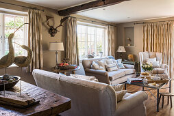 Neutral sofas with wall mounted antlers and bird ornaments in restored 16th century farmhouse