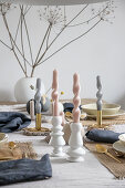 Arrangement of artistically twisted, pastel-coloured candles on table