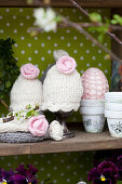 Knitted egg cosies with crocheted flowers