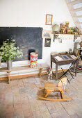 Rocking horse in front of an old bench, blackboard, and desk with junk as decoration