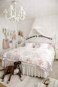 Dog at foot of bed with valance in romantic, white bedroom