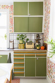Retro kitchen with green cabinets and floral wallpaper