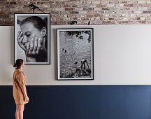 Woman looking at large-format, black and white framed photos on wall