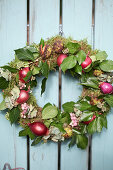 Autumn wreath with moss, ivy leaves, red onions, hydrangea blossoms, snowberries and chestnut shells