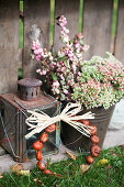 A small bouquet of stonecrop and snowberries, an old lantern, and a wreath of chestnuts