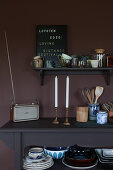 Regal und Konsole mit Geschirr vor dunkler Wand in der Küche