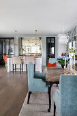 Elegant chairs with blue-grey upholstery in dining area of open-plan interior