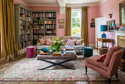 Upholstered furniture and bookshelves in living room with pink walls