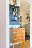 Old chest of drawers under dainty shelves mounted on blue-painted rectangle