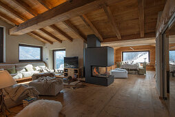 Open-plan interior with comfortable seating, wooden floor, wood-burning stove and wooden ceiling