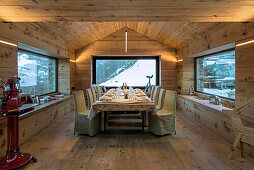 Langer, gedeckter Tisch mit Hussenstühlen im Esszimmer mit Holzverkleidung
