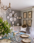 Set, round table below French chandelier; plates and botanical prints on the walls