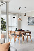 Various lamps above dining table and wooden upholstered chairs