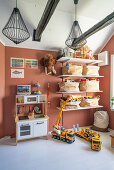 Children's play room with a kitchen, shelves, and toys with terracotta painted wall