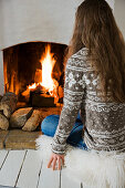 Woman wearing Norwegian jumper sitting in front of the fireplace