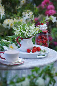 Bouquet of lilies of the valley in creamer pitcher on a tray with strawberries
