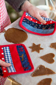 Hands holding a baking tray with gingerbread cookies with pot holder