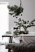 Weihnachtliche Tischdekoration mit Kiefernzweig und Strauß aus Eukalyptus und Mannstreu