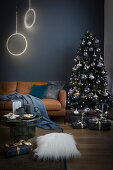 Ledersofa, Lichtobjekte und Weihnachtsbaum im Wohnzimmer mit blauer Wand