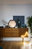 Glowing star in front of retro sideboard with Christmas decorations