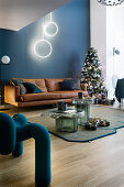 Ledersofa, Weihnachtsbaum und Designerstuhl im Wohnzimmer mit blauer Wand